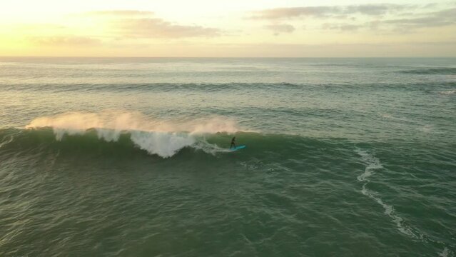 Surfer riding wave at sunset