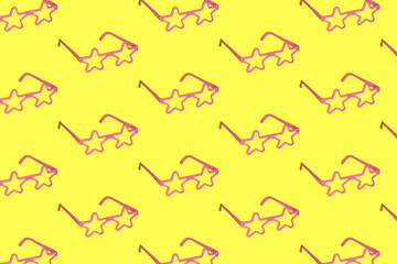 pink star-shaped glasses copied all over the yellow background. relaxed composition spring summer sunny day concept
