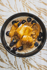 vegan soy milk oatmeail with peanut butter mango and blueberries topping, healthy plant-based food