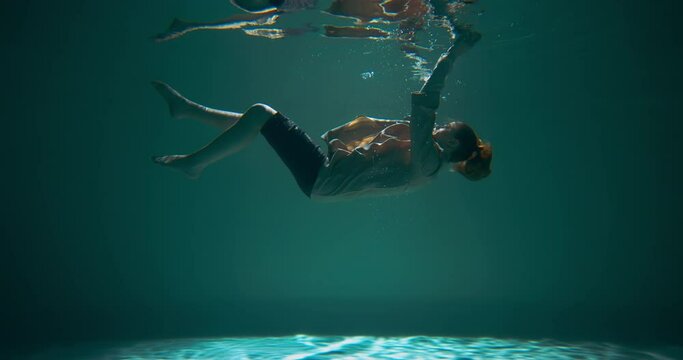 Depressed helpless young woman in business suit sinking underwater hits bottom. Emotional burnout concept slow motion.