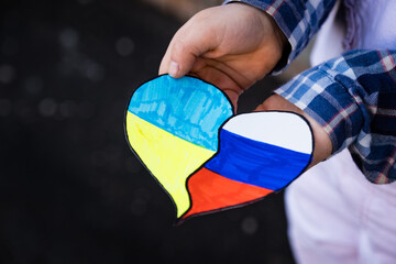 Ukrainian and Russian flags together in heart in child hands. Concept of ending the war in Ukraine and reconciliation