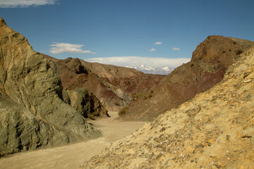 Andes mountains landscape. Transport. Dirt road in the arid desert mountains in Barreal, San Juan, Argentina. Geology. Rocky hills made of different minerals, with different colors and textures.