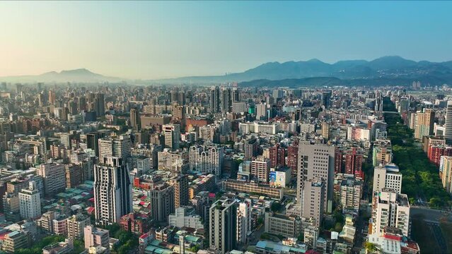 Aerial flyover beautiful Cityscape of Taipei with Skyscraper Buildings during sunny day with fog between mountains at horizon - Downtown with renai road in the morning