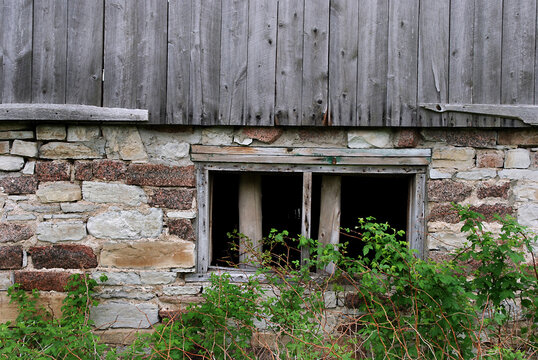 Old wooden window on side of stone barn wall