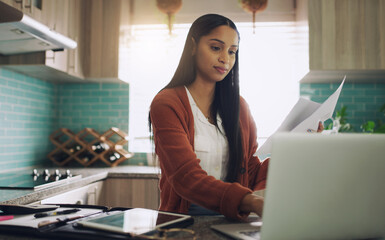 I like getting a productive start to my day. Shot of a young businesswoman working from home using...