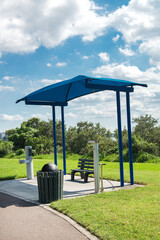 Fototapeta na wymiar bus stop with a canopy and a drinker. green lawn and blue sky
