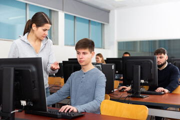 Fototapeta na wymiar Female teacher helping young male student in computer class in university. High quality photo