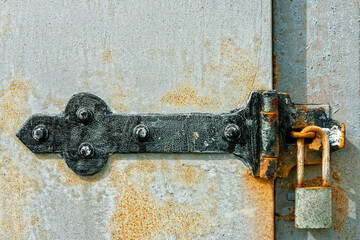 Close up of a rusty metal latch with a padlock