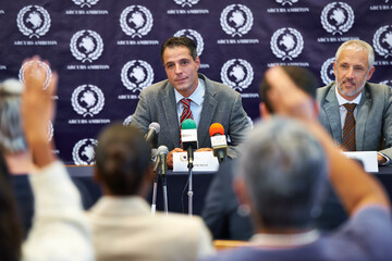 Any questions. Shot of a group of businesspeople in a press conference.