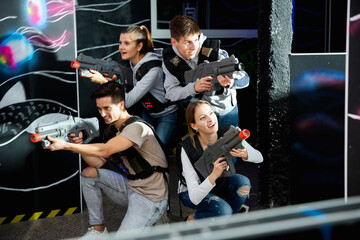 Smiling young friends playing laser tag game with colored laser. High quality photo