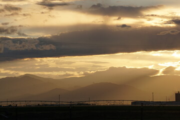 Naklejka premium Sunset over a farm and mountains. 