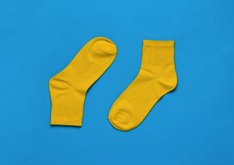 A pair of bright yellow sports socks on a bright blue background. Flat lay.
