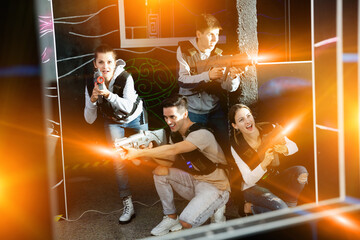 Group of adult people with laser guns having fun on dark lasertag arena. High quality photo