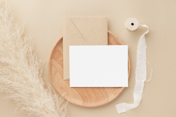 Blank greeting card invitation Mockup on Brown envelope with pampas grass on beige background,...