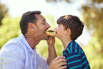 Whos got the biggest bite. Shot of a father and son biting into a sandwich at the same time.