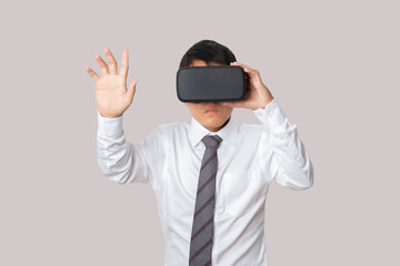 Studio portrait businessman wearing VR Headset touching something isolated on gray background.