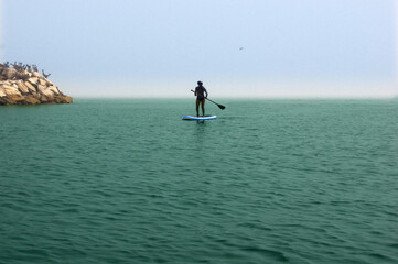 paddle standing, silhouette of young woman on the beach at cloudy day