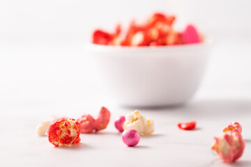 Colorful red and pink candied popcorn with mixed candies in bowl