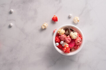 Colorful red and pink candied popcorn with mixed candies in bowl