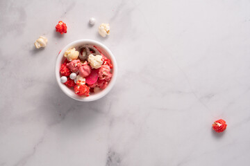 Colorful red and pink candied popcorn with mixed candies in bowl