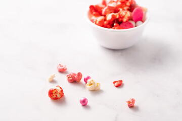 Colorful red and pink candied popcorn with mixed candies in bowl