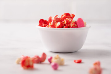 Colorful red and pink candied popcorn with mixed candies in bowl