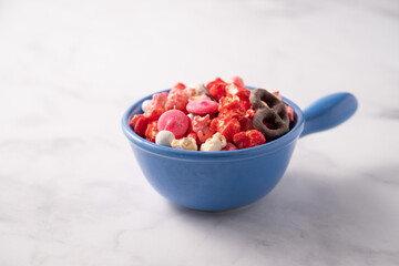 Colorful red and pink candied popcorn with mixed candies in bowl