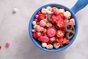 Colorful red and pink candied popcorn with mixed candies in bowl