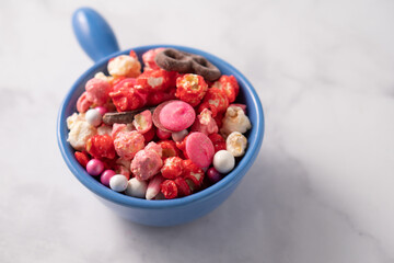 Colorful red and pink candied popcorn with mixed candies in bowl