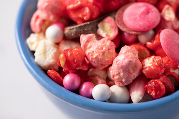 Colorful red and pink candied popcorn with mixed candies in bowl