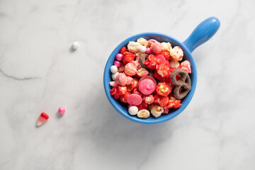 Colorful red and pink candied popcorn with mixed candies in bowl