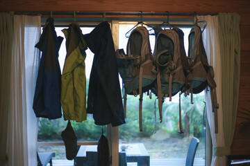 clothes and backpacks hanging on a hanger in a mountain house.
