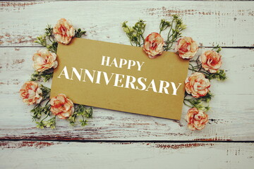 Happy Anniversary typography text decorate with flower on wooden background