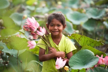Tuinposter A girl with a perfect smile holding a lotus flower and looking at the camera. Portrait of a young girl smiling happily. © somchai20162516