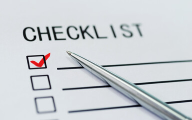 Checklist with checkmark and pen on paper