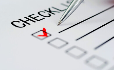 Checklist with checkmark and pen on paper