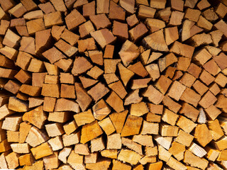 Firewood cut and stacked. Wall of wooden pieces. Warm colors with shades of brown. Wood stacked with precision. Wooden natural cut logs texture background
