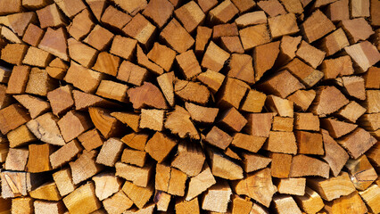 Firewood cut and stacked. Wall of wooden pieces. Warm colors with shades of brown. Wood stacked with precision. Wooden natural cut logs texture background