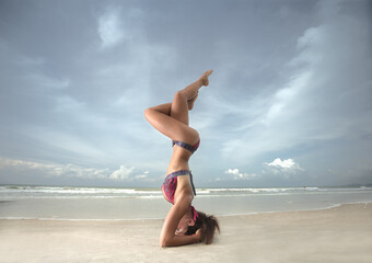 Fototapeta na wymiar Young woman practicing yoga on the beach