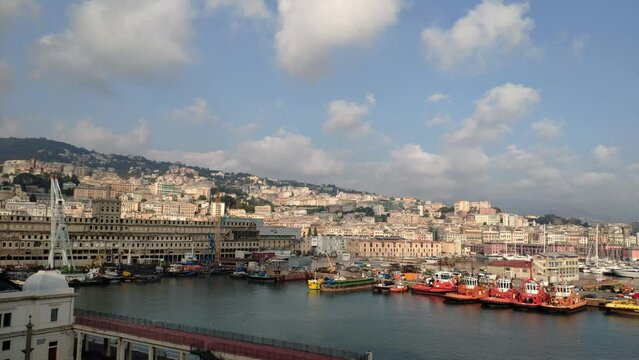 Time lapse of port of La Spezia, Cinque Terre, Italy. Horizon behind with hills full of houses and green areas. Beautiful cloud formations moving in the sky. Different boats anchored. Many tugboats.