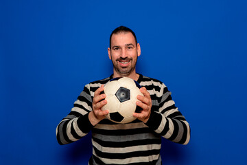 Photo of young excited man happy positive smile hold ball game football fan champion isolated over blue color background