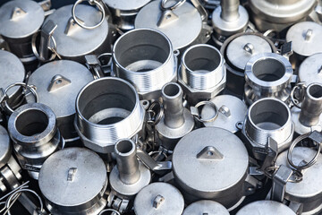 New bushings, couplings, threaded connections and nipples made of stainless steel. A pile of steel fittings close-up.