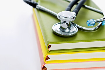 Stethoscope and pile of books on white background