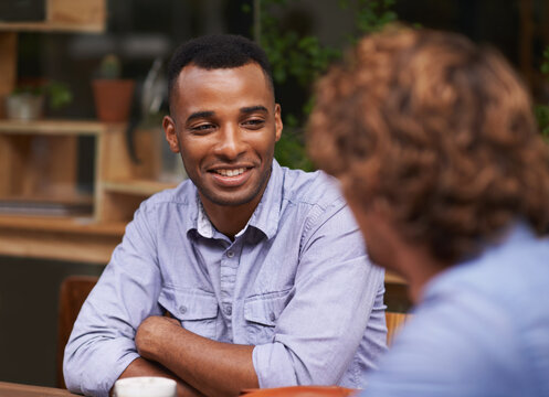 Catching Up With An Old Friend. A Handsome Young Man Sitting With A Friend At A Cafe.