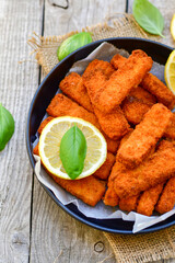 Close up of   Crispy breaded  deep fried fish fingers with breadcrumbs served  with remoulade sauce and  lemon Cod Fish Nuggets on rustic wood table background