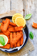 Close up of   Crispy breaded  deep fried Fish Fingers with breadcrumbs served  with remoulade sauce and  lemon Cod Fish Nuggets on rustic wood table background