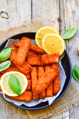Close up of   Crispy breaded  deep fried Fish Fingers with breadcrumbs served  with remoulade sauce and  lemon Cod Fish Nuggets on rustic wood table background