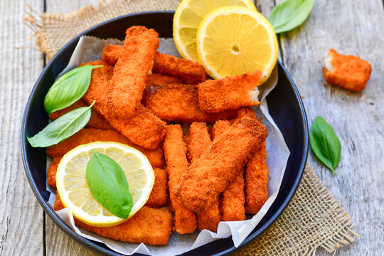 Close up of   Crispy breaded  deep fried Fish Fingers with breadcrumbs served  with remoulade sauce and  lemon Cod Fish Nuggets on rustic wood table background