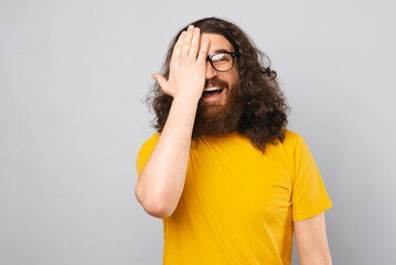 Exhilarated bearded man is covering one eye while smiling at the camera.