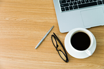 Fototapeta na wymiar Desk with laptop, coffee, pen and eyeglasses